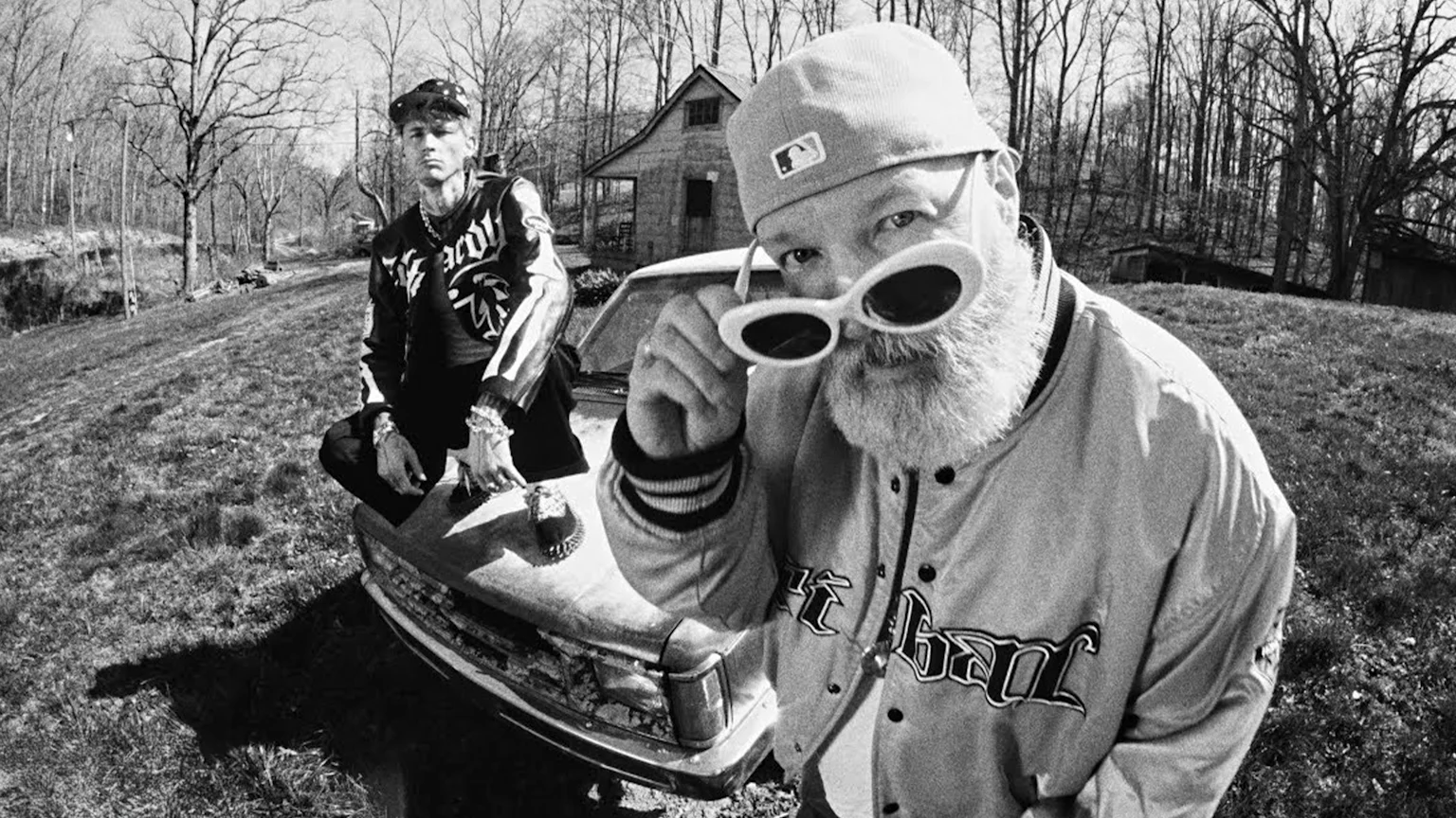 Fred Durst and MGK in a black and white image sitting on an old car