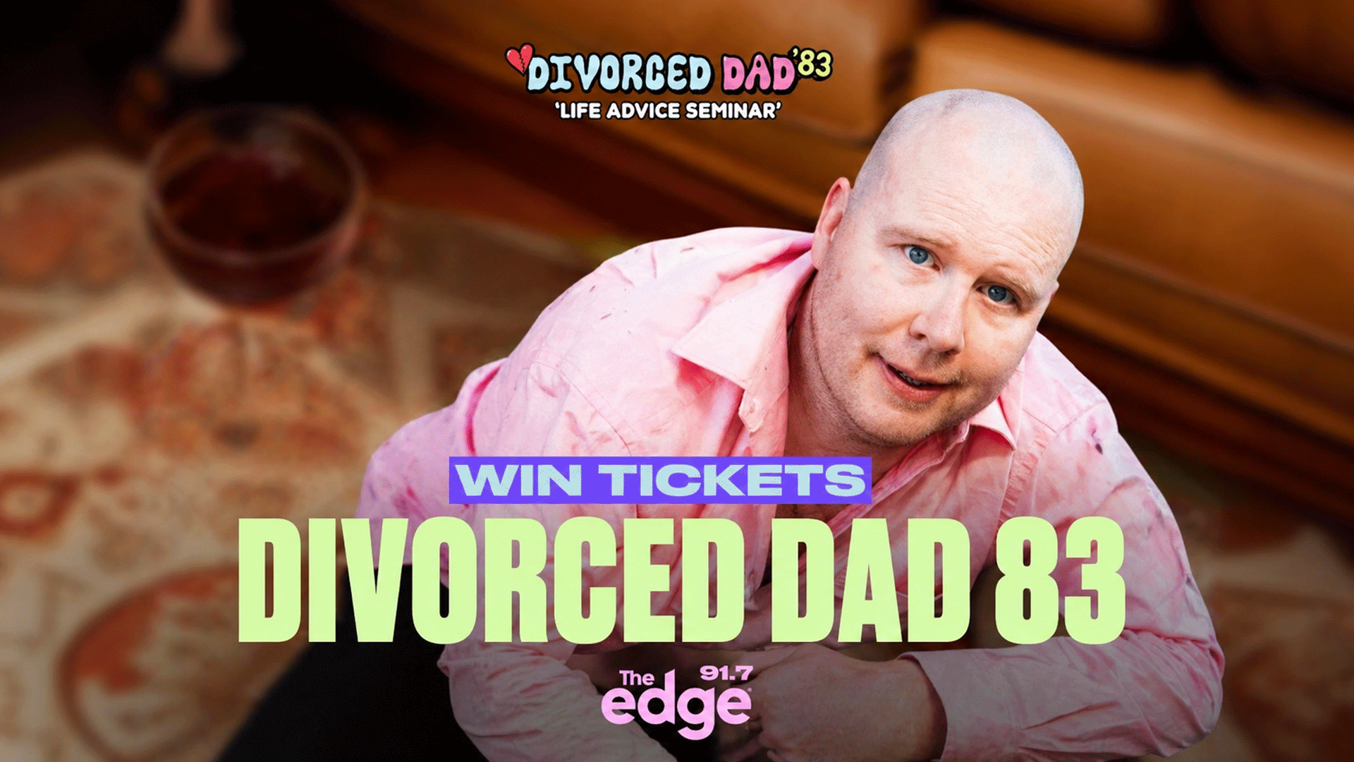 A smiling bald man in a pink shirt appears with "WIN TICKETS DIVORCED DAD 83" text, a smaller "DIVORCED DAD '83 'LIFE ADVICE SEMINAR'" logo, and "The 91.7 edge" branding, all over a blurred background with a wine glass.