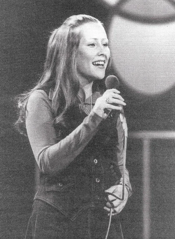 Suzanne Prentice at 15 years old on stage singing with a microphone in hand.