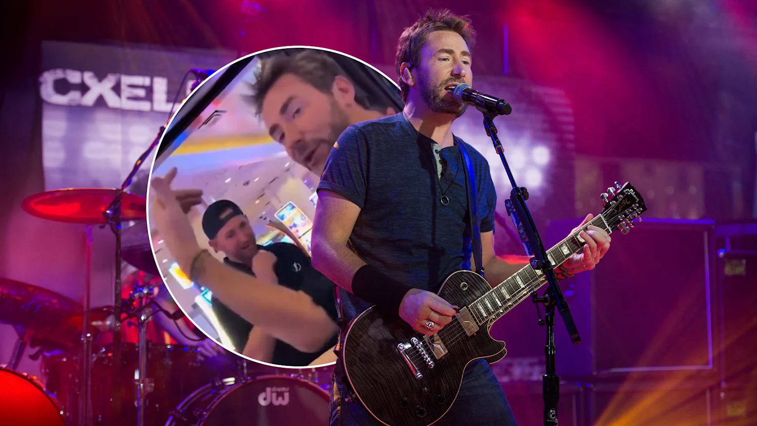 A fair-skinned male musician in his 40s sings and plays a dark Les Paul-style electric guitar on a concert stage, illuminated by red, purple, and orange lights. Behind him are a red DW drum kit, a black amplifier cabinet, and a banner reading 'CXEL'. An inset shows two men interacting indoors in bright ambient lighting.