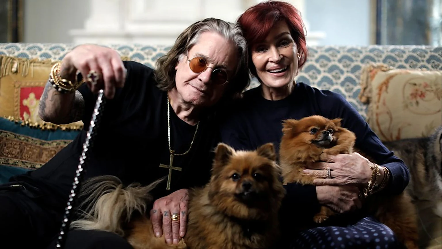 Sharon and Ozzy Osbourne on the couch with their two dogs.