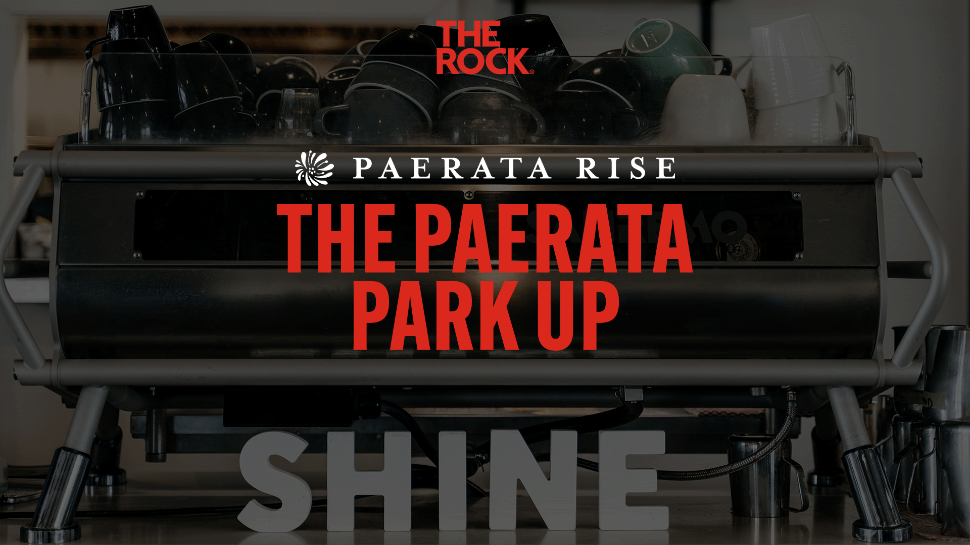 An espresso machine with coffee cups, featuring "THE ROCK" logo, "PAERATA RISE" with a floral logo, "THE PAERATA PARK UP" in red text, and "SHINE" in grey 3D letters.