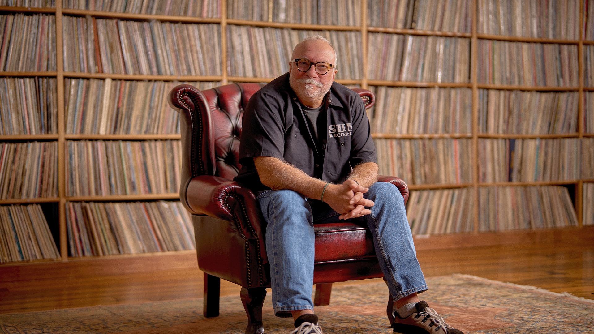 Bob Gentil sitting in a leather chair in front of a wall of vinyl records