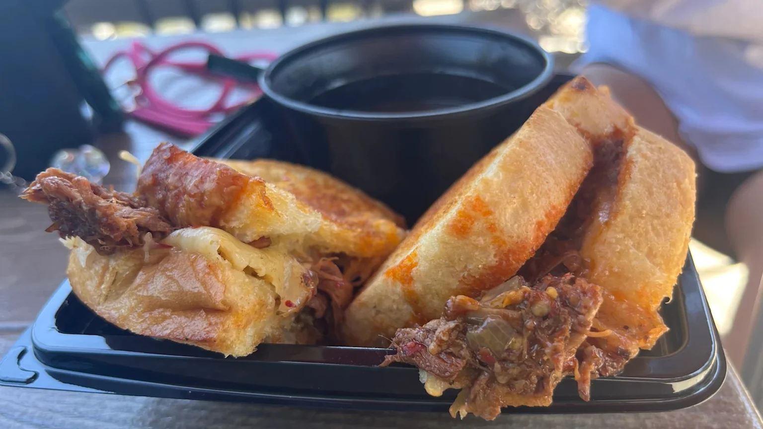 A tray holding a birria toastie and consomme.