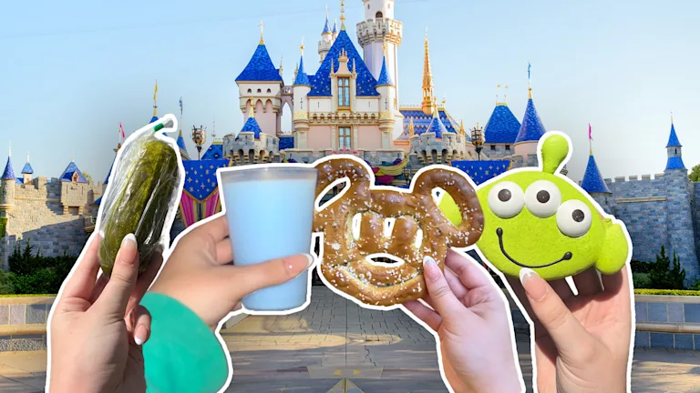 Pickle, cup of blue milk, Mickey Mouse-shaped pretzel and 'Toy Story' Alien macaron held up in front of the Disneyland California Sleeping Beauty Castle.