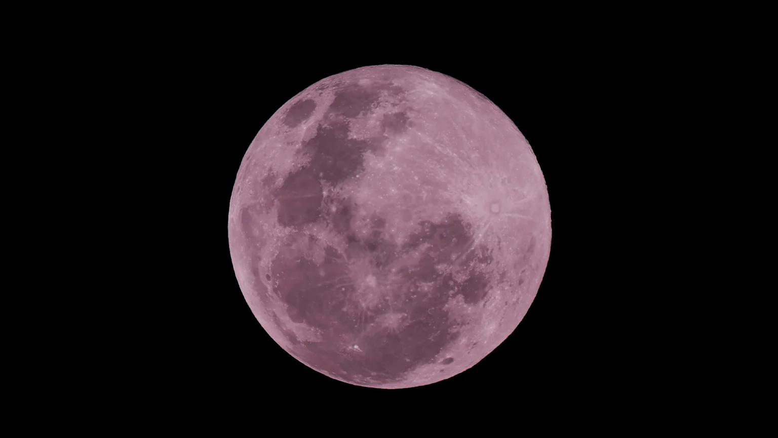A large, detailed pink full moon with visible craters against a black night sky.
