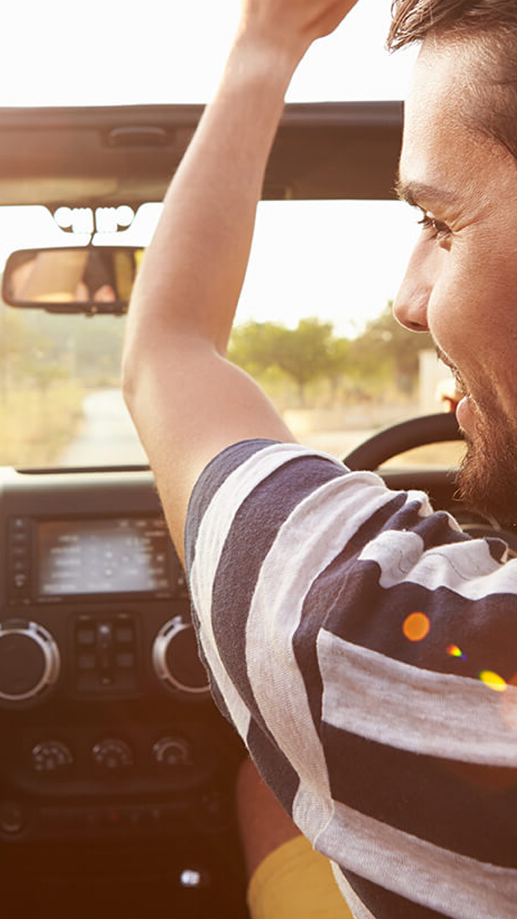 man enjoying sunny road trip in car