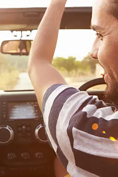 man enjoying sunny road trip in car