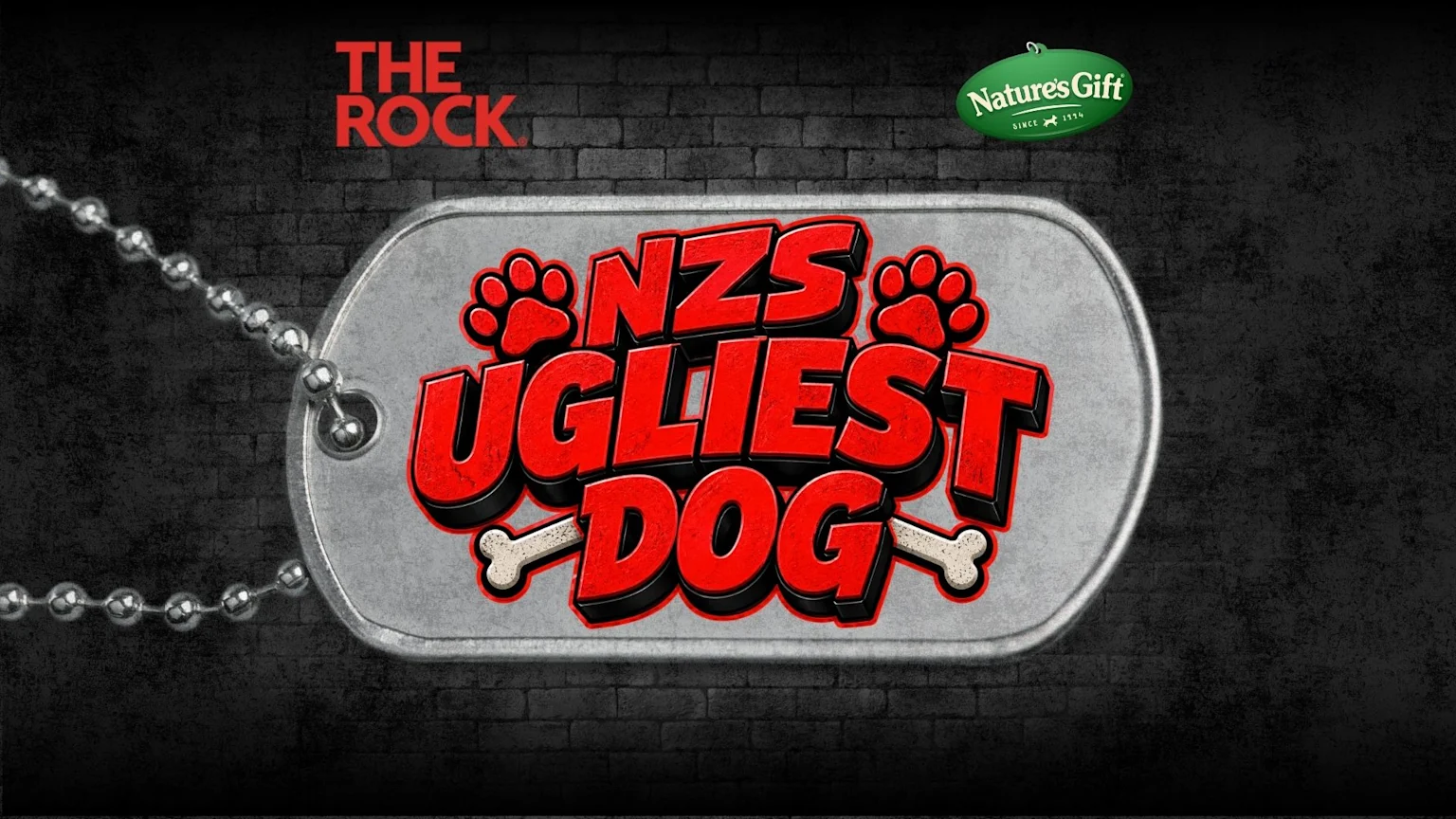 A silver dog tag with "NZS UGLIEST DOG" in red text, accented by paw prints and bones, lies against a dark brick wall, with "THE ROCK" and "Nature's Gift" logos also visible.