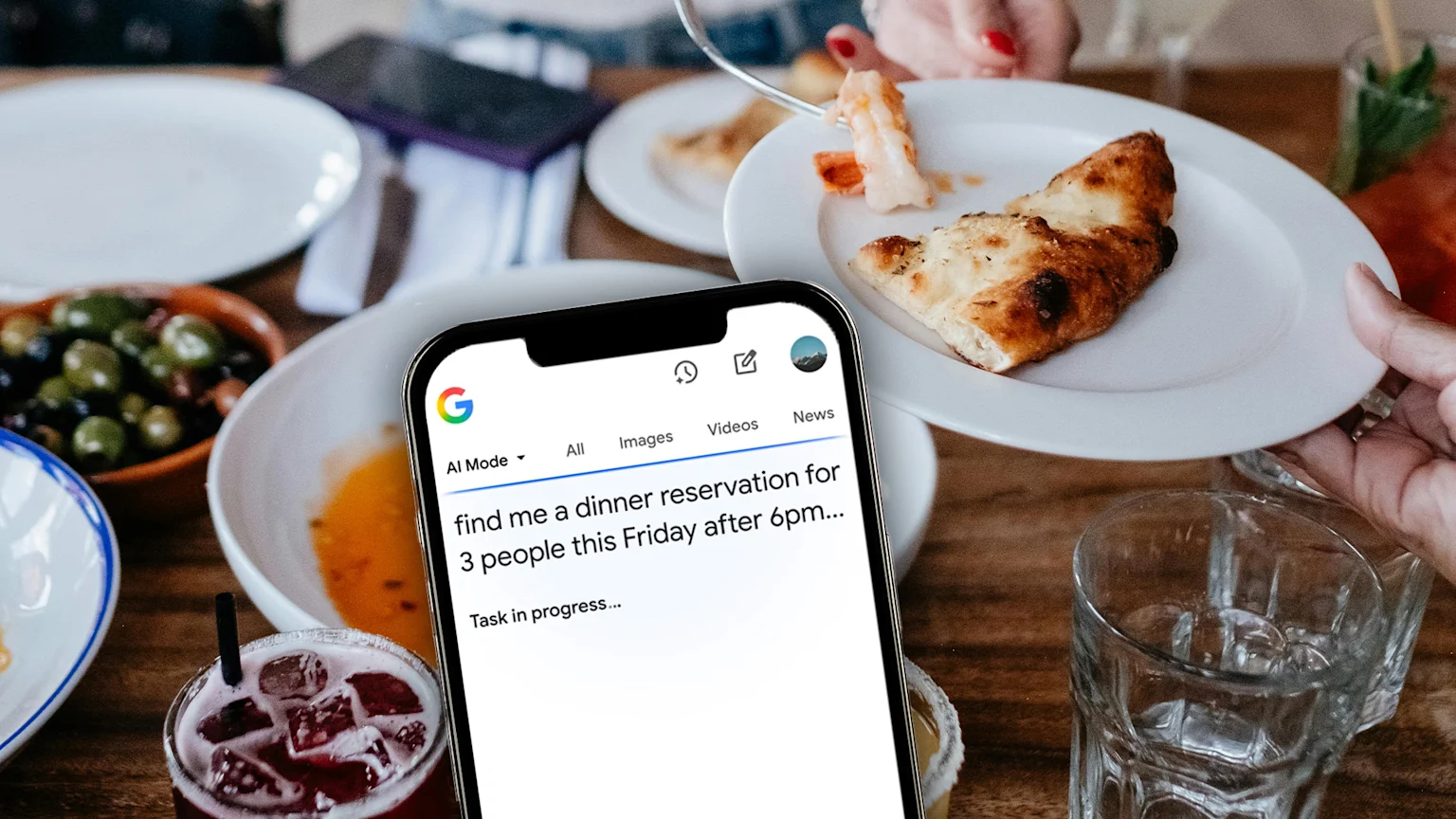 A smartphone displays a Google search for "dinner reservation for 3 people" over a blurred image of a dining table with food and drinks, including a plate of flatbread being served.
