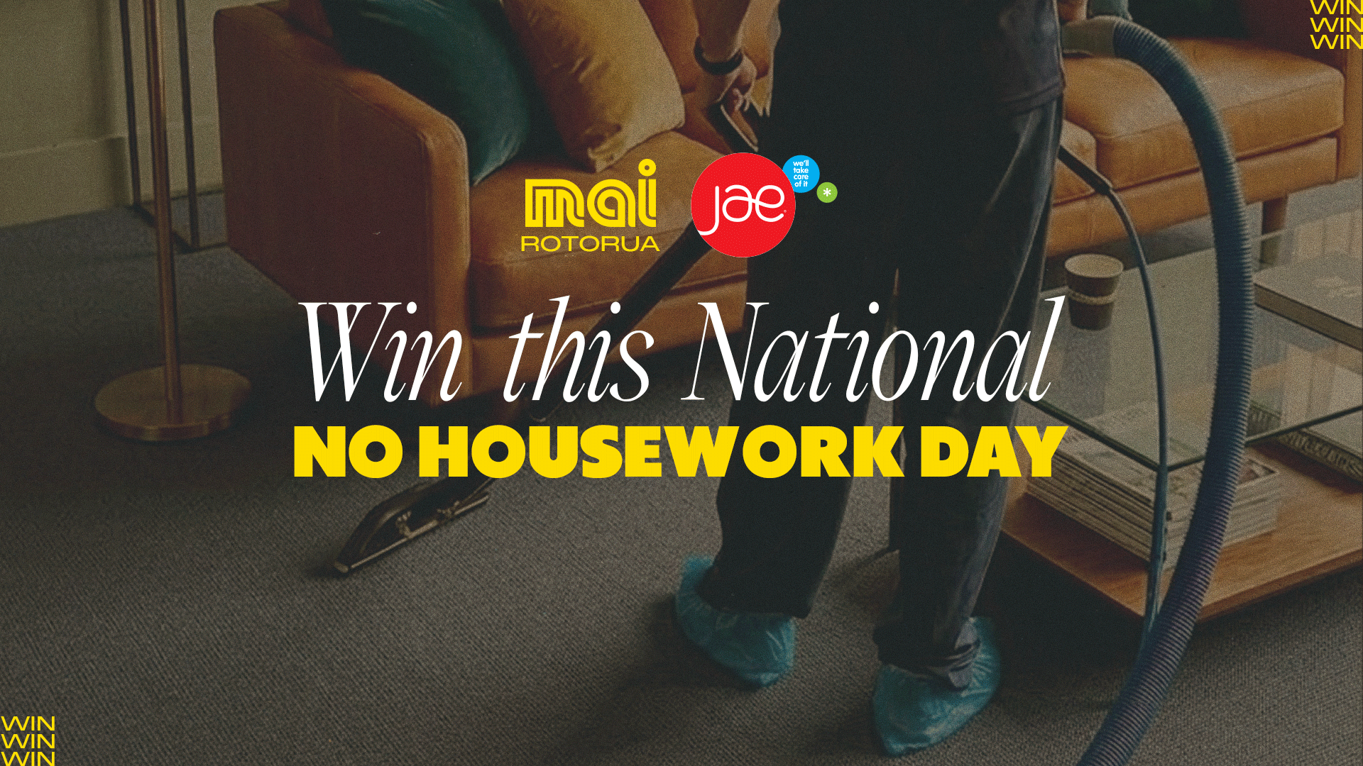 A person wearing blue shoe covers uses a vacuum cleaner to clean a grey carpet in a living room, with the Jae Cleaning logo and promotional text "Win this National NO HOUSEWORK DAY" visible.