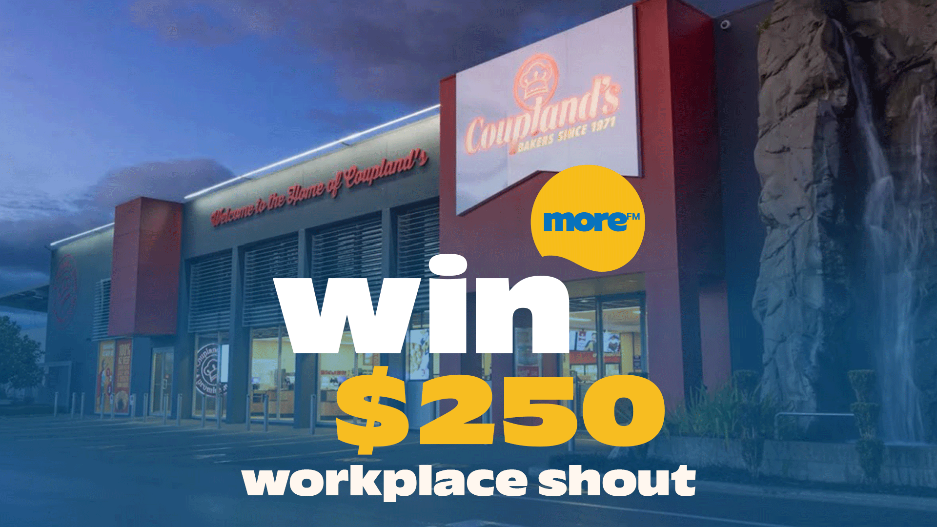 A Coupland's bakery building at dusk, with "win $250 workplace shout" in large text and the More FM logo superimposed, next to a rock formation with a waterfall.