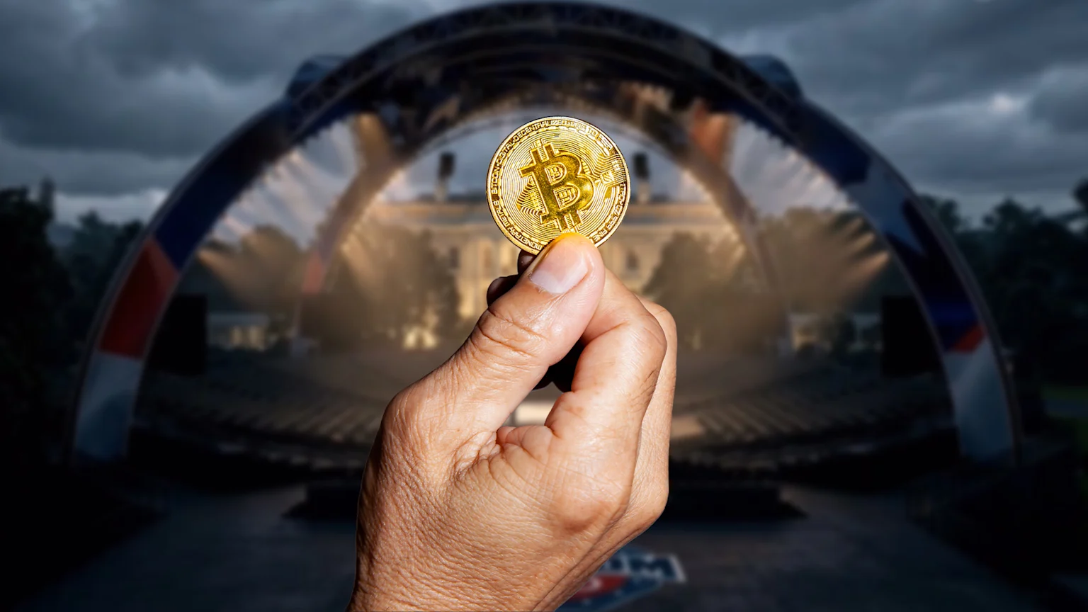 A gold Bitcoin coin is held by a hand in the foreground, with a blurred outdoor stage featuring patriotic arches and a building resembling the White House in the background.