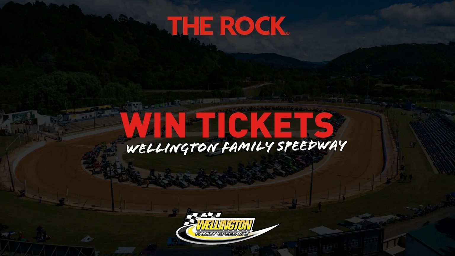 Aerial view of Wellington Family Speedway with many race cars on a dirt track, grandstands, and green hills, featuring "THE ROCK" and "WIN TICKETS" text overlays.
