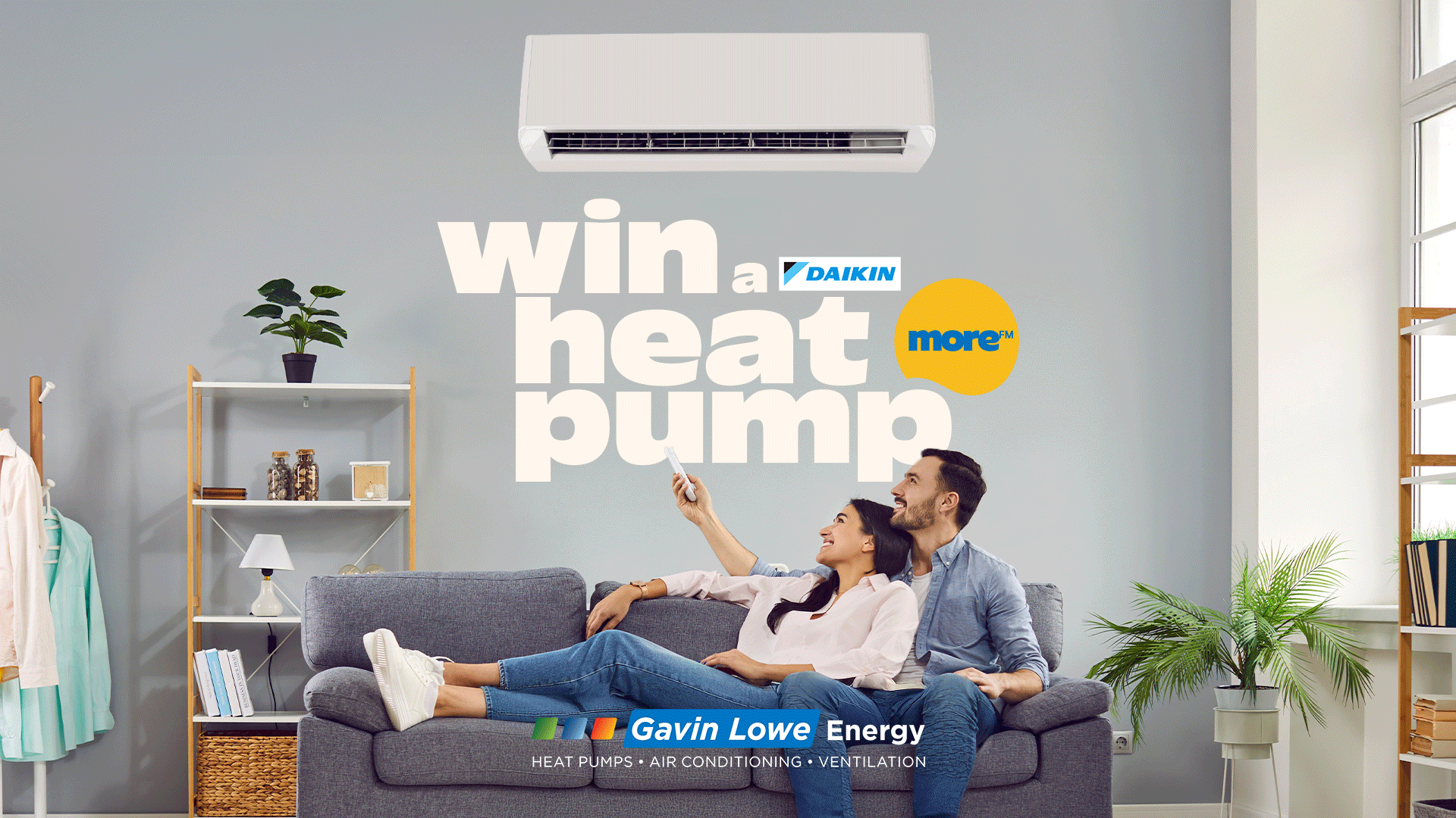 A smiling couple on a sofa looks up at a wall-mounted heat pump, with text "win a DAIKIN heat pump" and "Gavin Lowe Energy" branding in a modern living room.