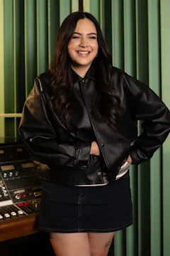 Shay is standing against a green wall.