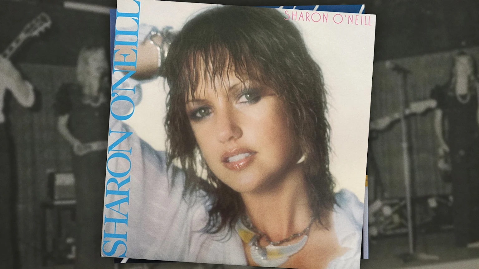 Sharon O'Neill self self-titled album cover overlayed on a blurred background of her and a band performing at a pub in 1974.
