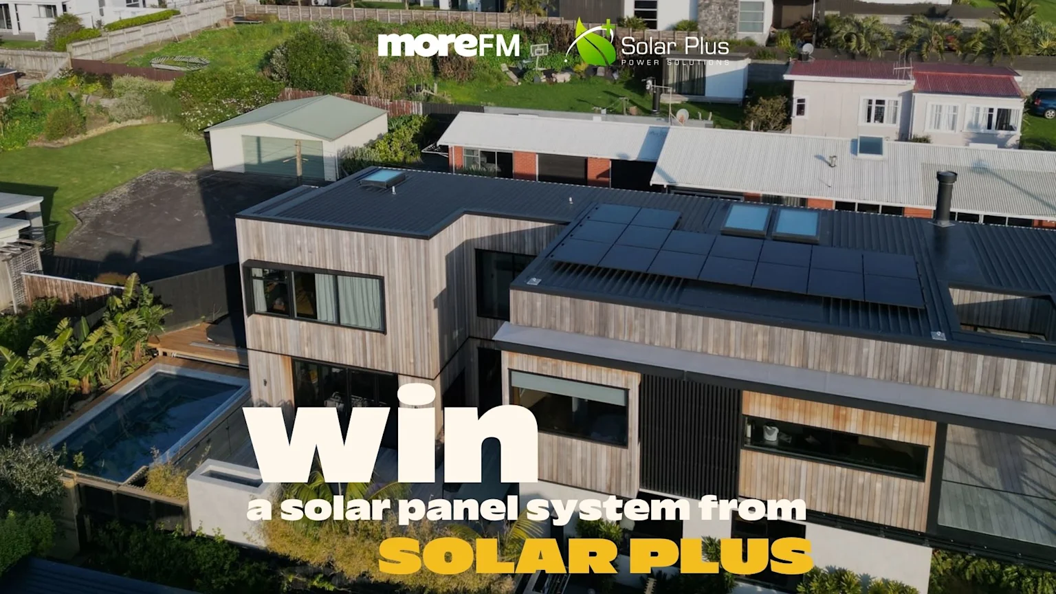 An aerial view of a modern house with solar panels on the roof and a pool, overlaid with the text "Win a solar panel system from SOLAR PLUS" and company logos.