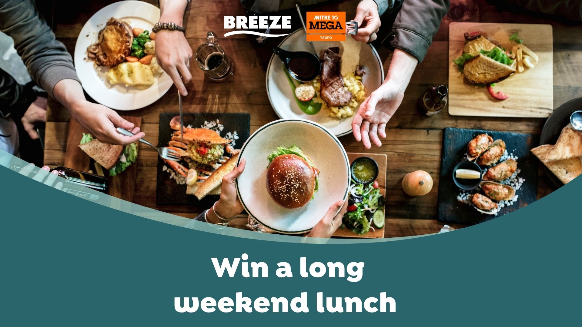 An overhead shot shows multiple hands around a wooden table laden with various lunch dishes like a burger, crab, steak, pie, oysters, and salads, with text "Win a long weekend lunch".