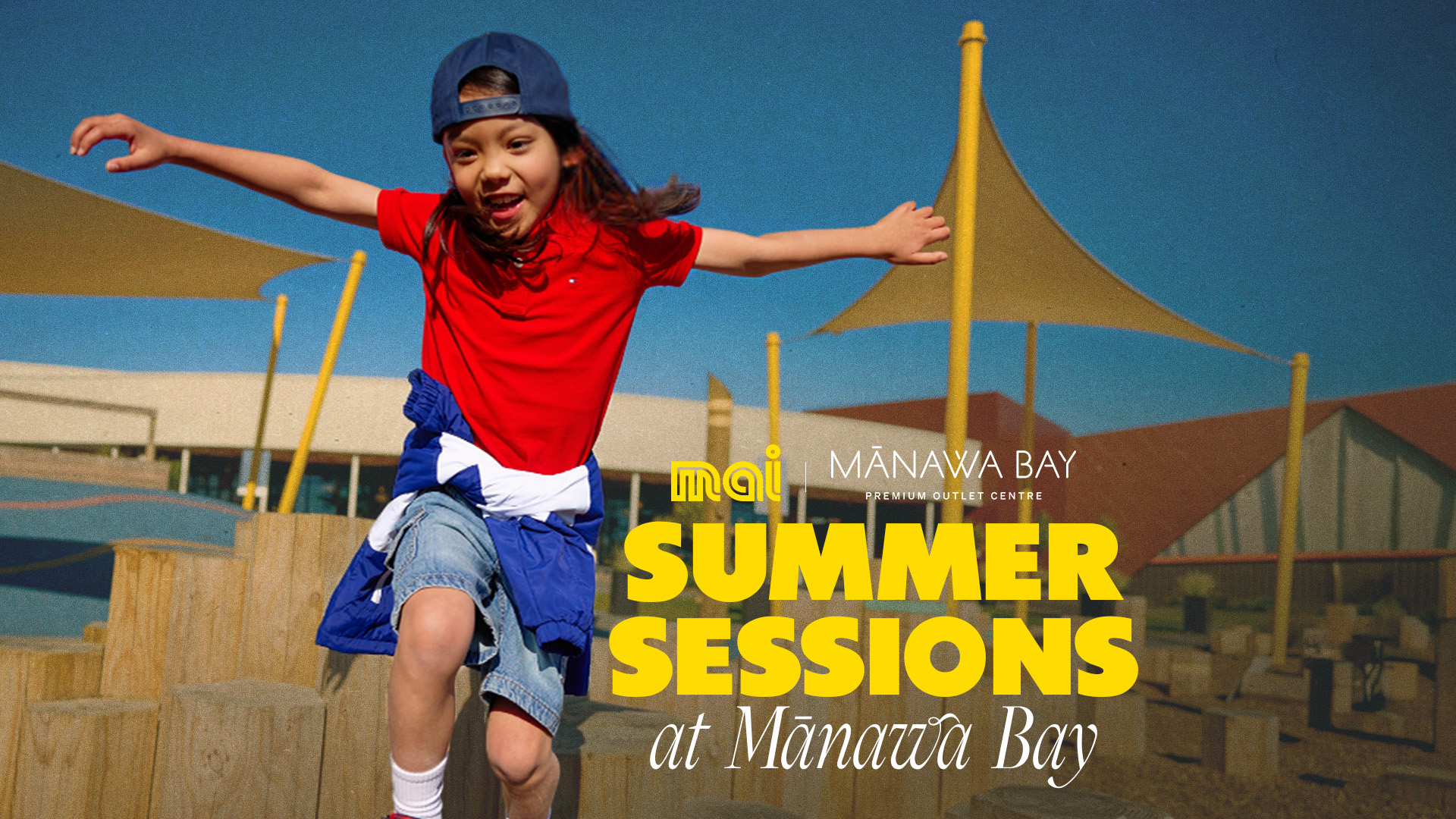 Kid in red shirt and denim shorts with cap jumping off playground. "Summer Sessions at Mānawa Bay" with Mai FM Auckland