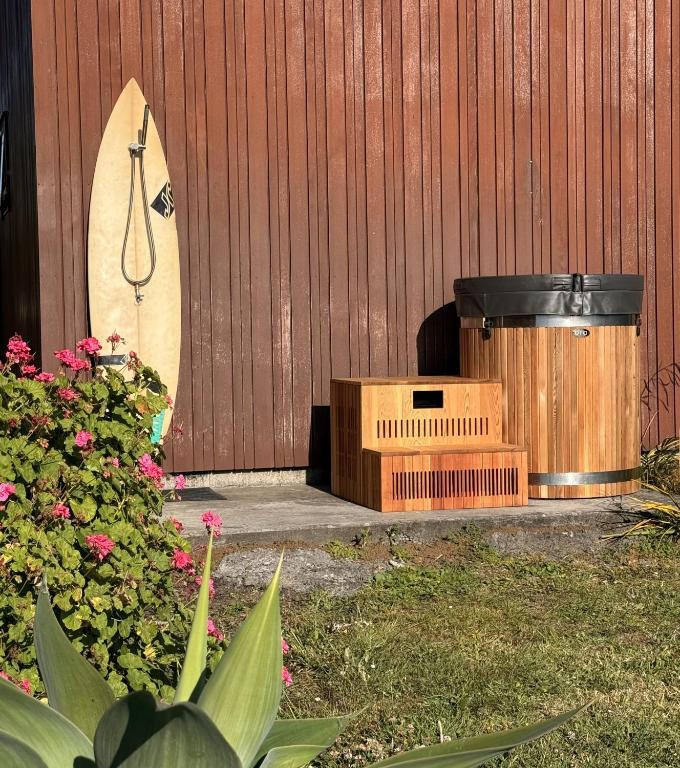 Surfboard and hot tub by wooden wall