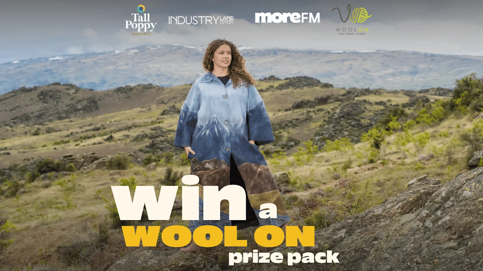 A woman in a blue mountain-themed coat stands on a rocky hill under logos for Tall Poppy, Industry Lane Eatery, moreFM, and WoolOn, with text reading "win a WOOL ON prize pack".