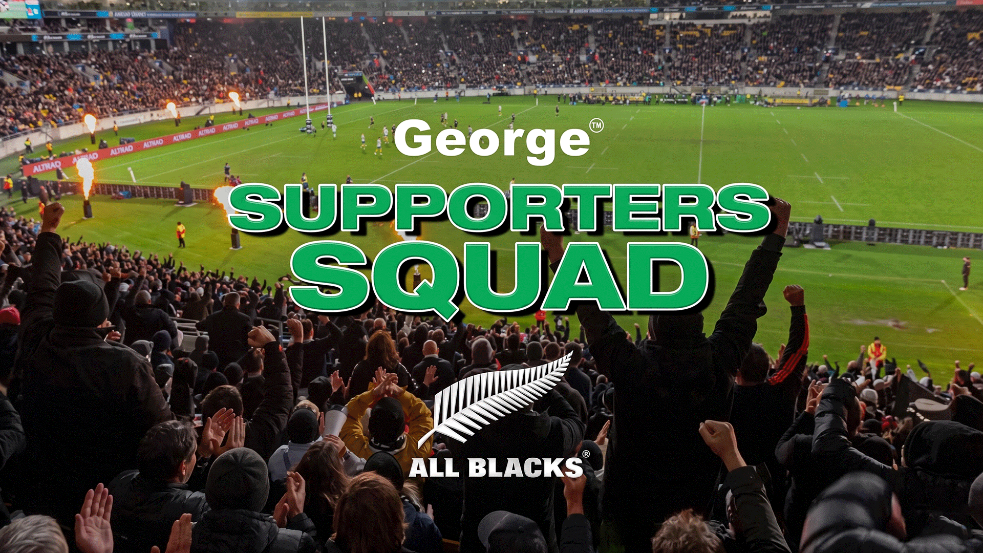 A stadium packed with cheering All Blacks supporters at a night rugby game with pyrotechnics, featuring "George SUPPORTERS SQUAD" and "ALL BLACKS" text.