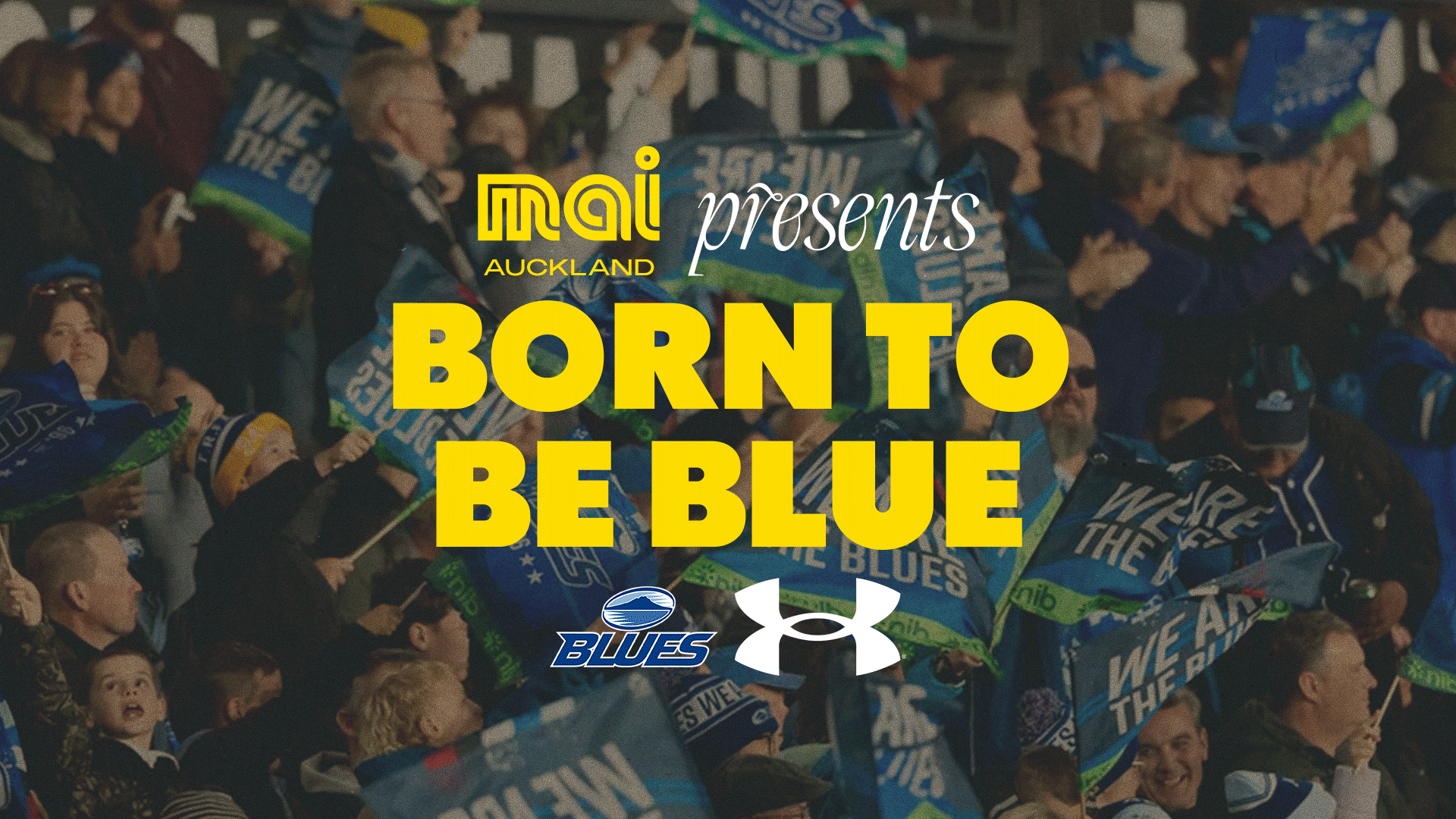 A cheering crowd of fans, many holding blue flags, beneath the text 'MAI AUCKLAND presents BORN TO BE BLUE' and logos for Mai, Blues, and Under Armour.
