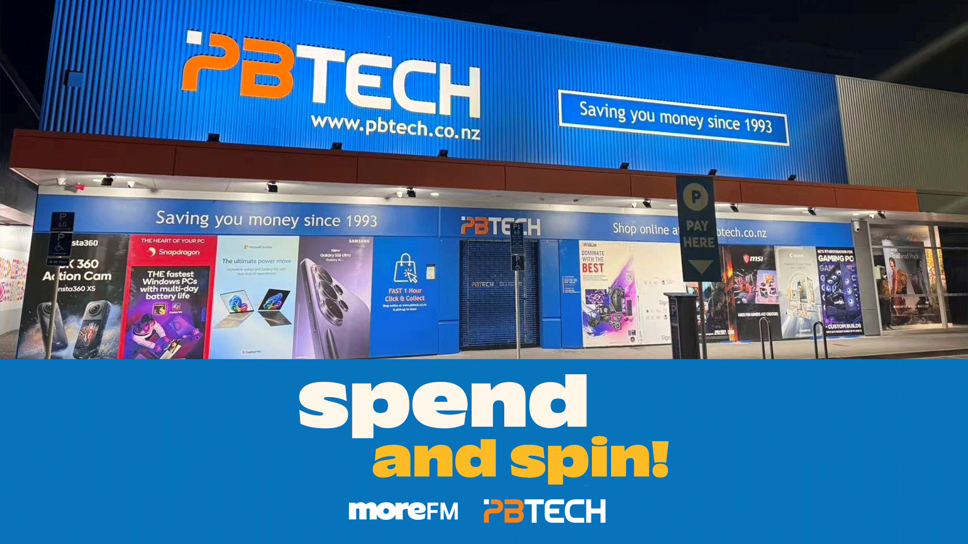 Exterior view of a PB Tech electronics store at night, featuring its prominent blue and white sign, storefront displays, and an overlay that reads 'spend and spin! moreFM PBTECH'.