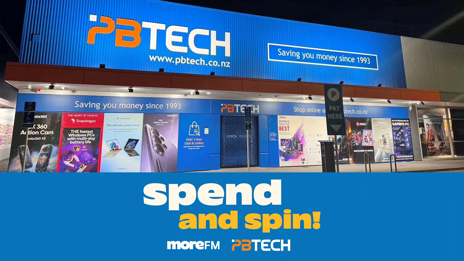 Exterior view of a PB Tech electronics store at night, featuring its prominent blue and white sign, storefront displays, and an overlay that reads 'spend and spin! moreFM PBTECH'.