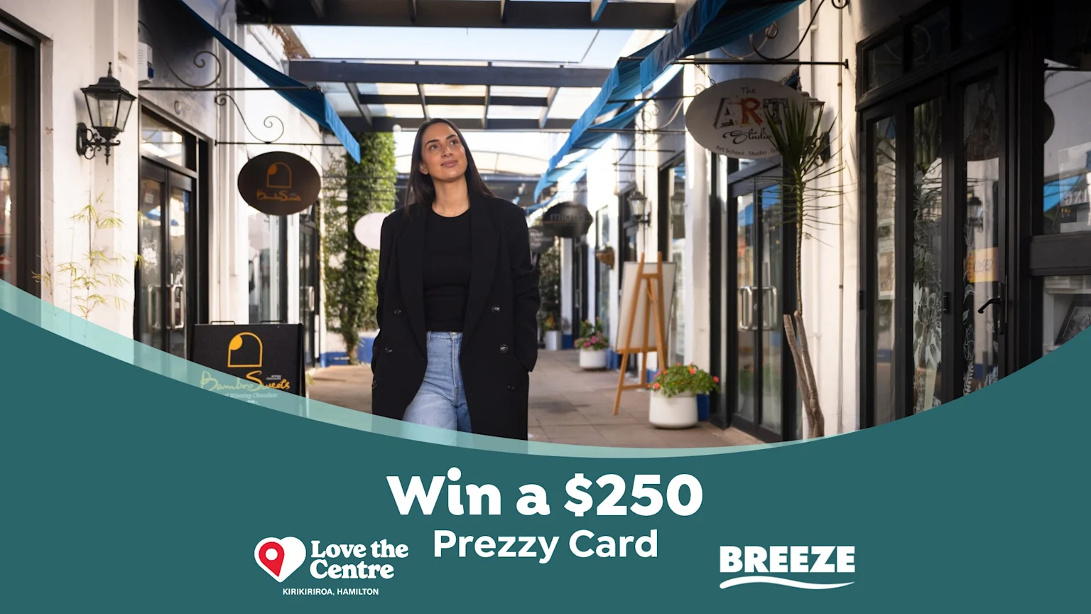 A woman walks through an outdoor shopping arcade lined with businesses and awnings, with promotional text "Win a $250 Prezzy Card" and "Love the Centre" and "BREEZE" logos at the bottom.
