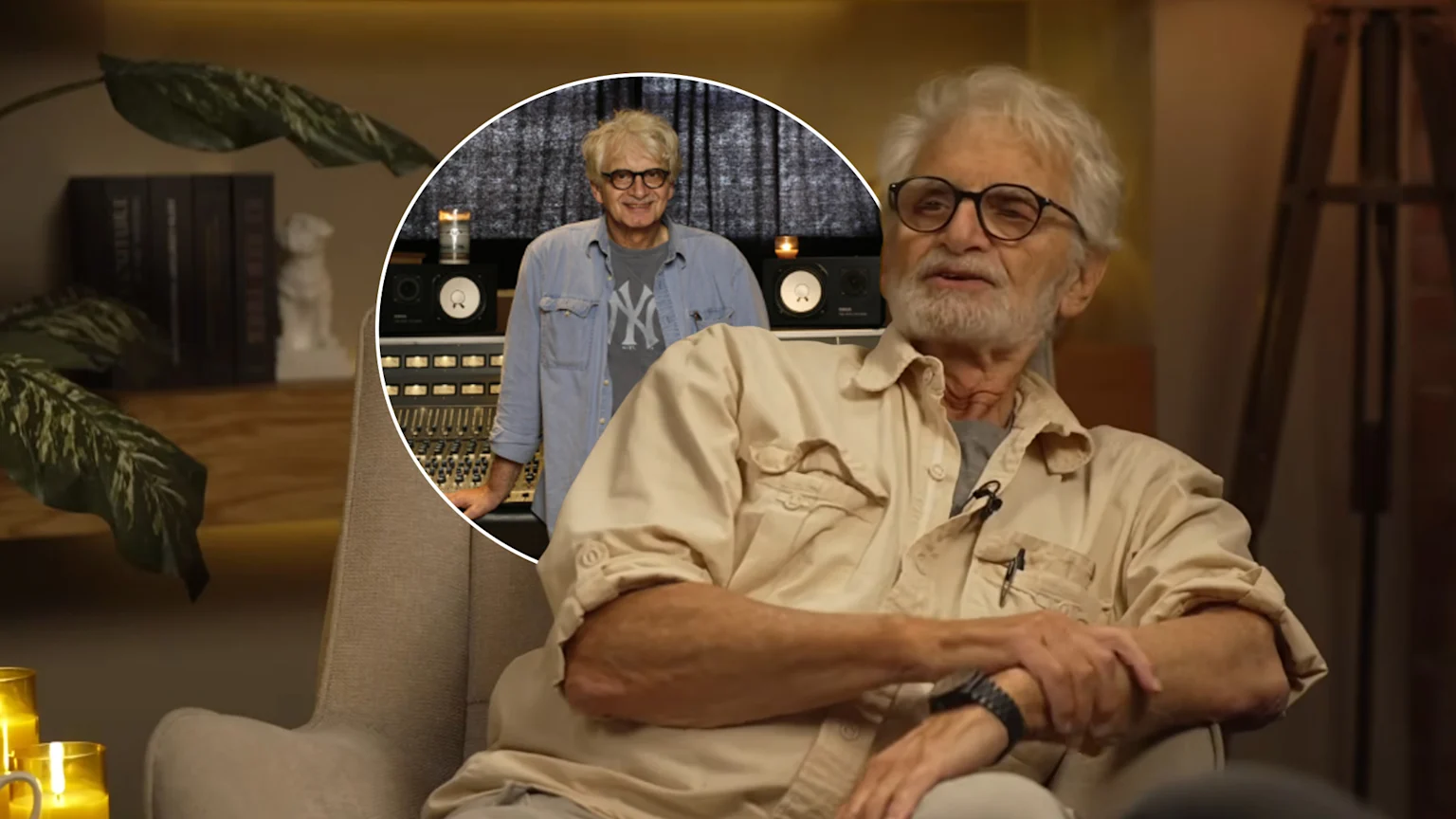 An older man with white hair, beard, and glasses in a beige shirt sits in an armchair, while a circular inset shows him smiling in a recording studio, wearing a denim shirt and a NY t-shirt.