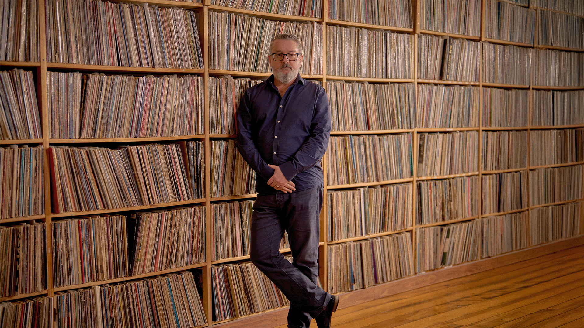 Mark Smith standing in front of vinyl record collection wall
