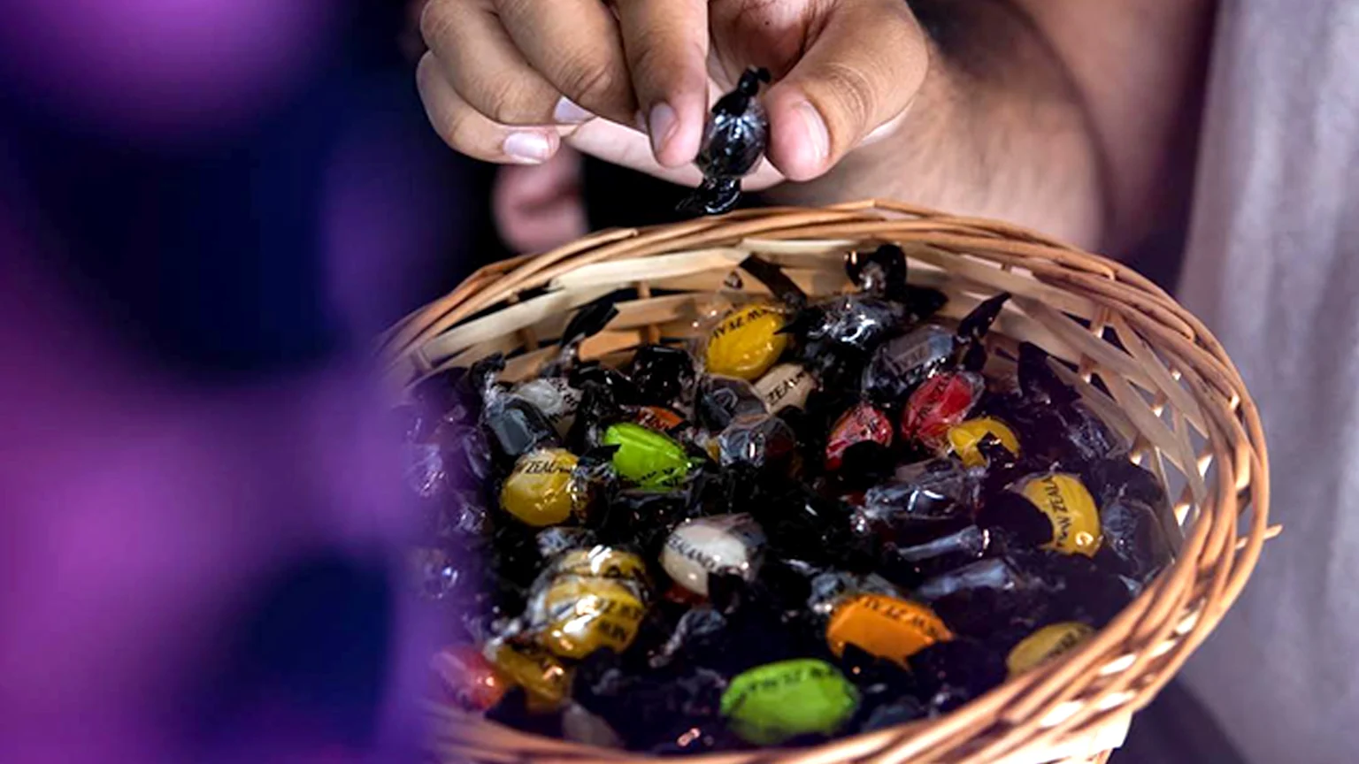 A flight attendant holding a basket of air new zealand lollies.