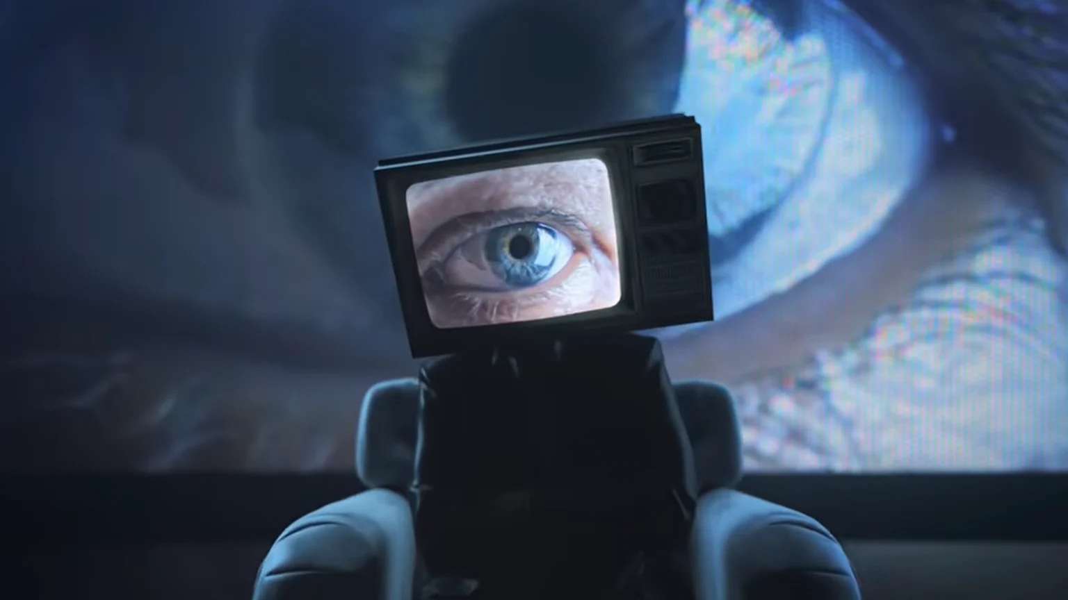 A dark figure with a vintage TV for a head, displaying a blue eye, sits in a chair facing a large wall projecting a giant blue eye.