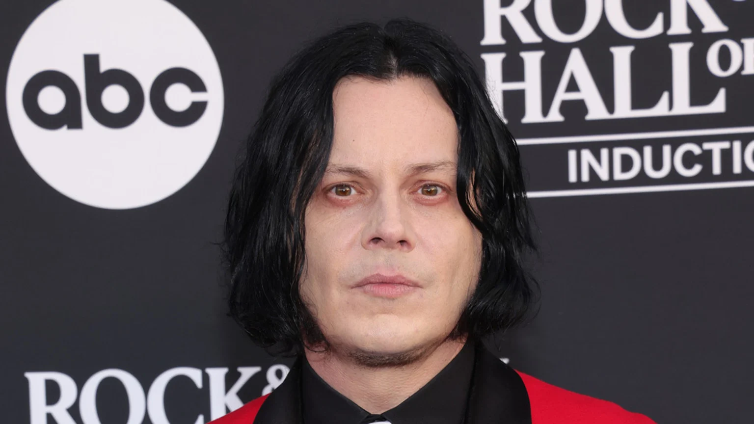 A pale-skinned man with dark, shoulder-length hair and a red jacket looks forward, with an "abc" logo and "ROCK & ROLL HALL OF FAME INDUCTION" text on a black background.
