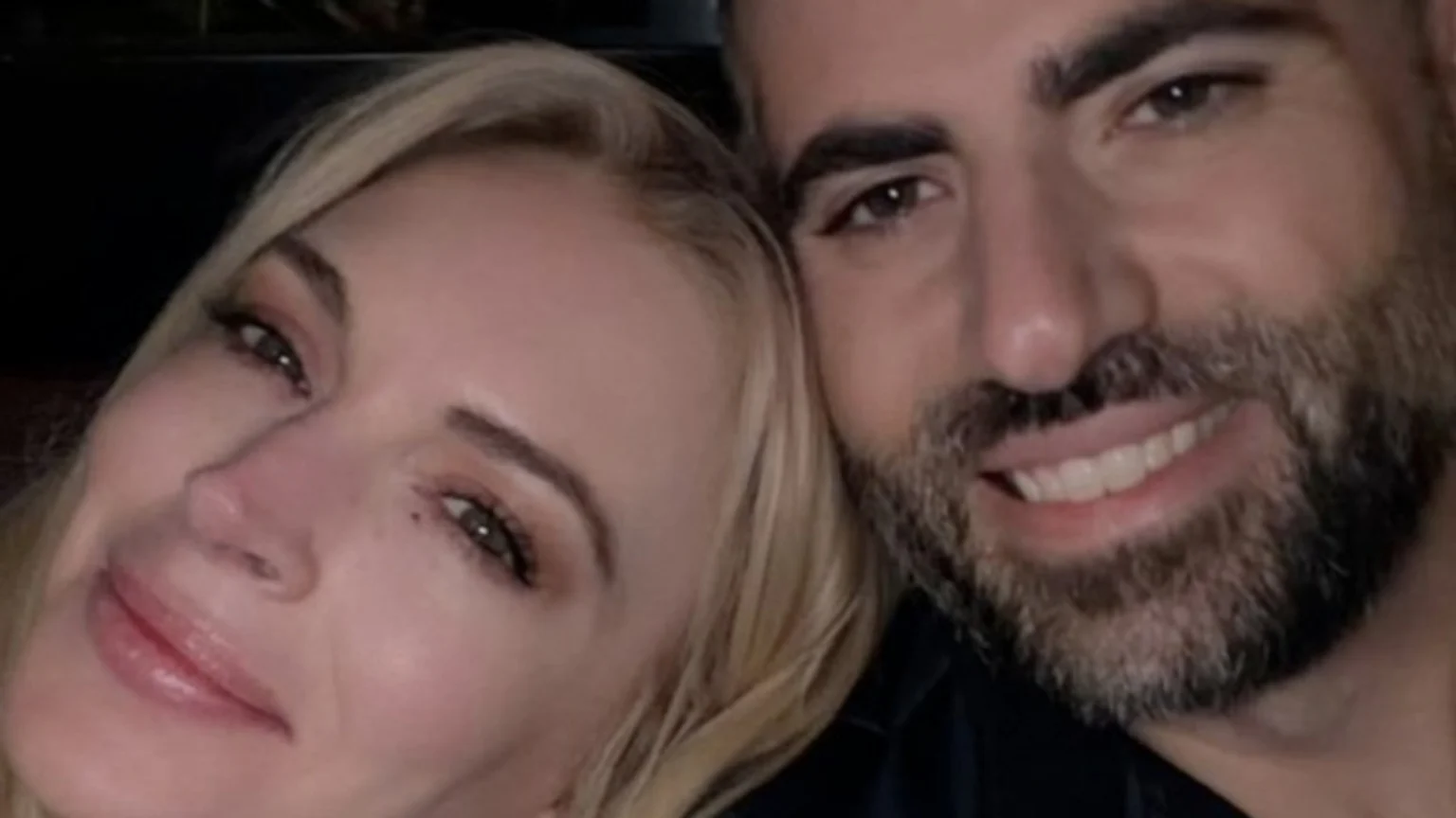 A close-up shot of Lindsay Lohan and Bader Shammas. Lohan, with blonde hair, smiles gently on the left, while Shammas, with a beard, smiles broadly on the right.