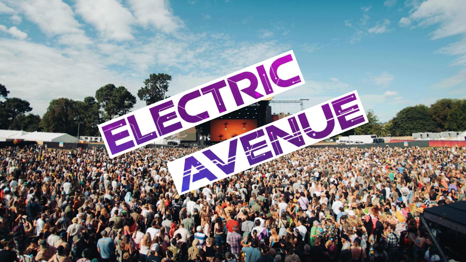 A wide shot of a large crowd attending an outdoor music festival under a partly cloudy sky, with a stage in the background and the words "ELECTRIC AVENUE" overlaid on the image.