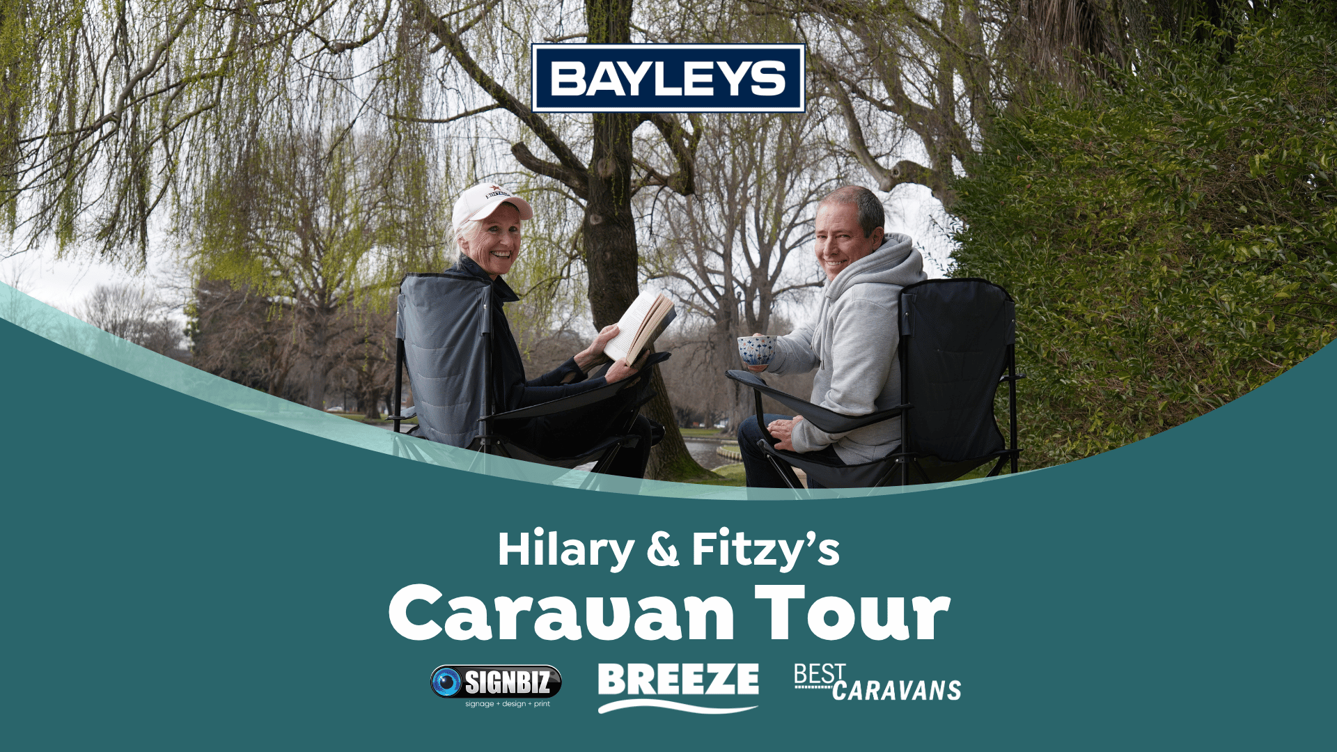 A smiling woman reads a book and a smiling man holds a cup, both seated in camping chairs outdoors among trees, with a Bayleys logo above them and "Hilary & Fitzy's Caravan Tour" text and sponsor logos on a graphic below.