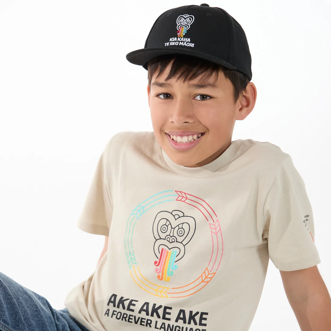 Child wearing Māori language t-shirt and cap