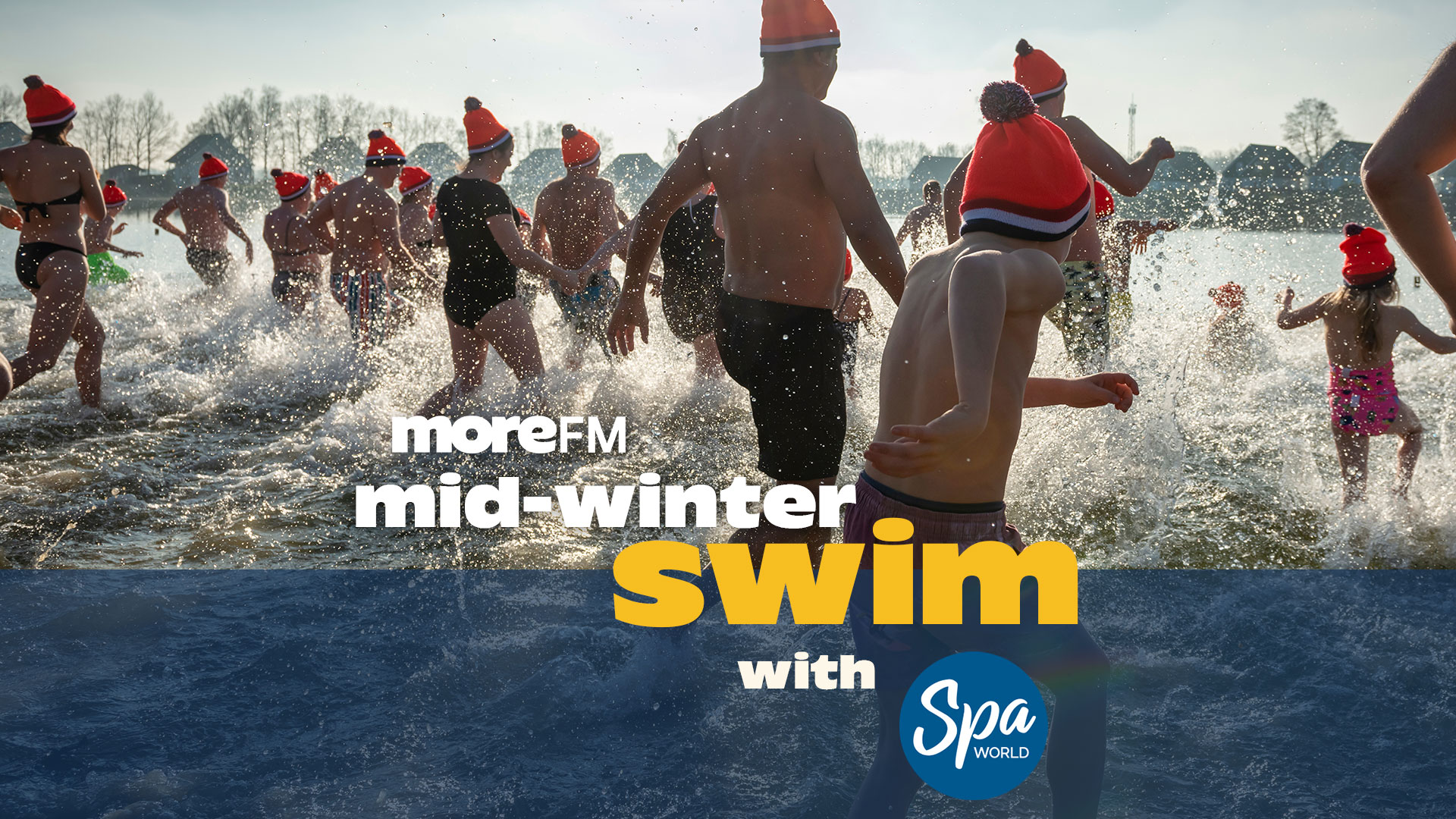A diverse group of people, many wearing orange hats, run and splash through water in a mid-winter swim event, with text overlay: "moreFM mid-winter swim with Spa World".
