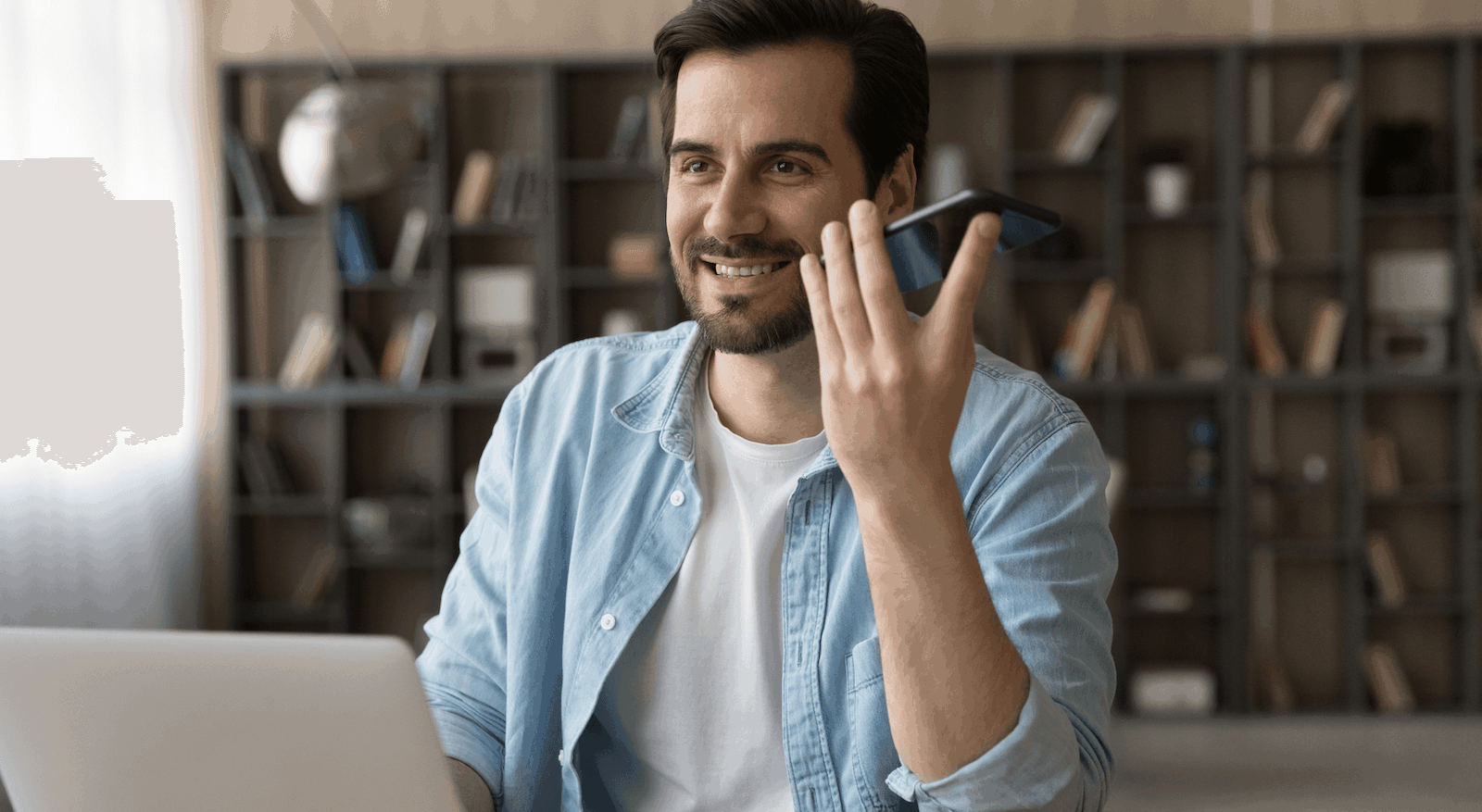 A man in a blue shirt making a call on his phone.