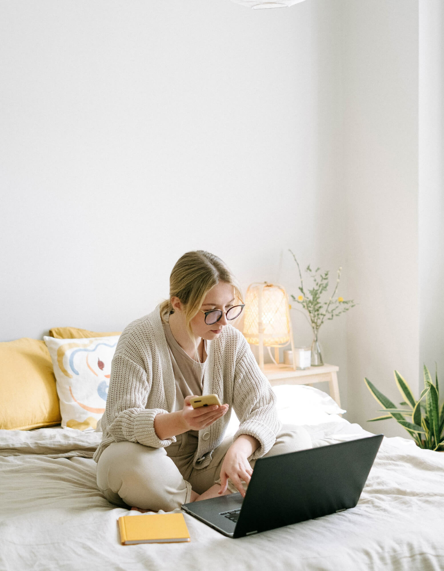 woman sitting on a bed working on her laptop