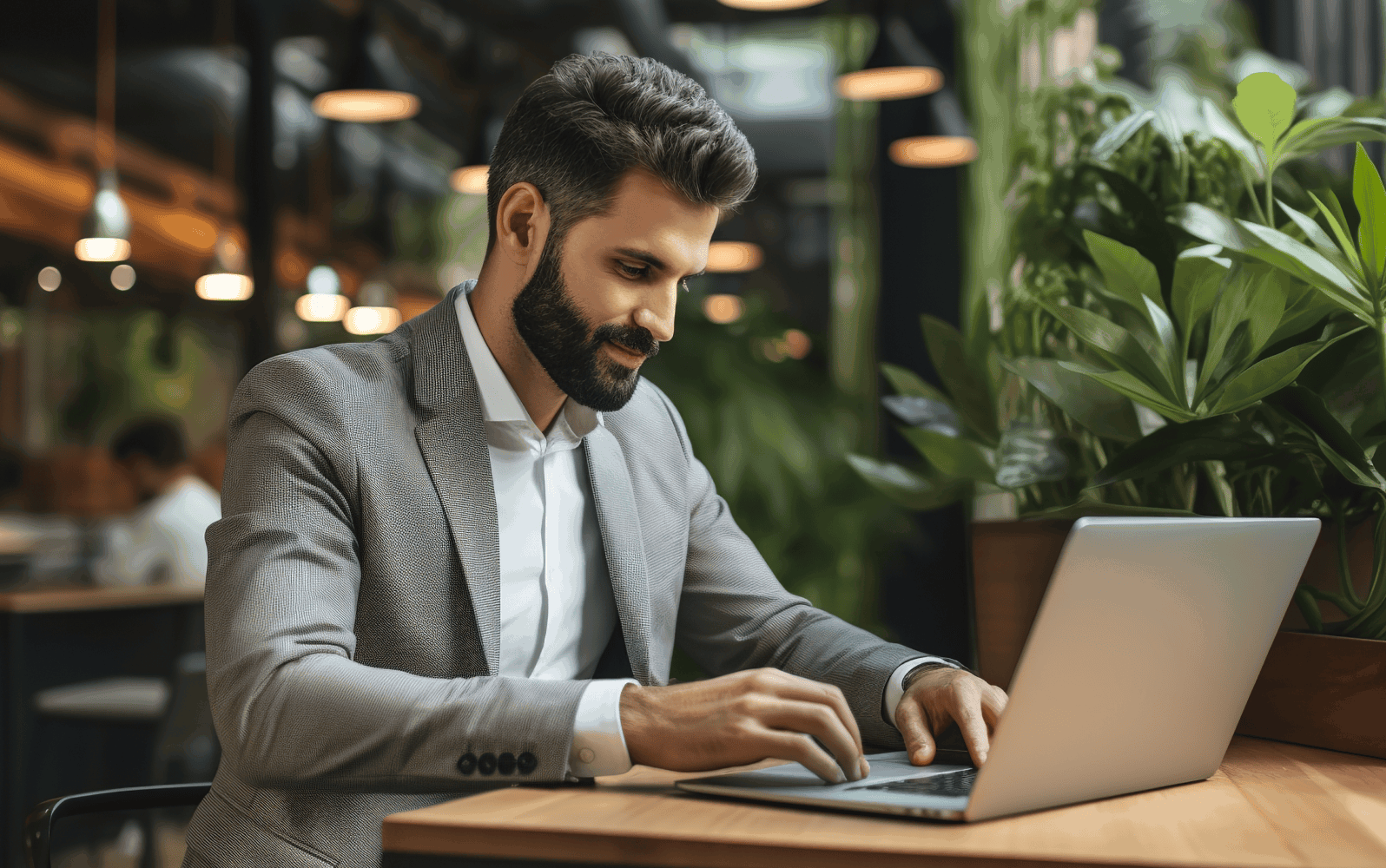 Man wearing a suit sitting at a desk with a laptop in front of them
