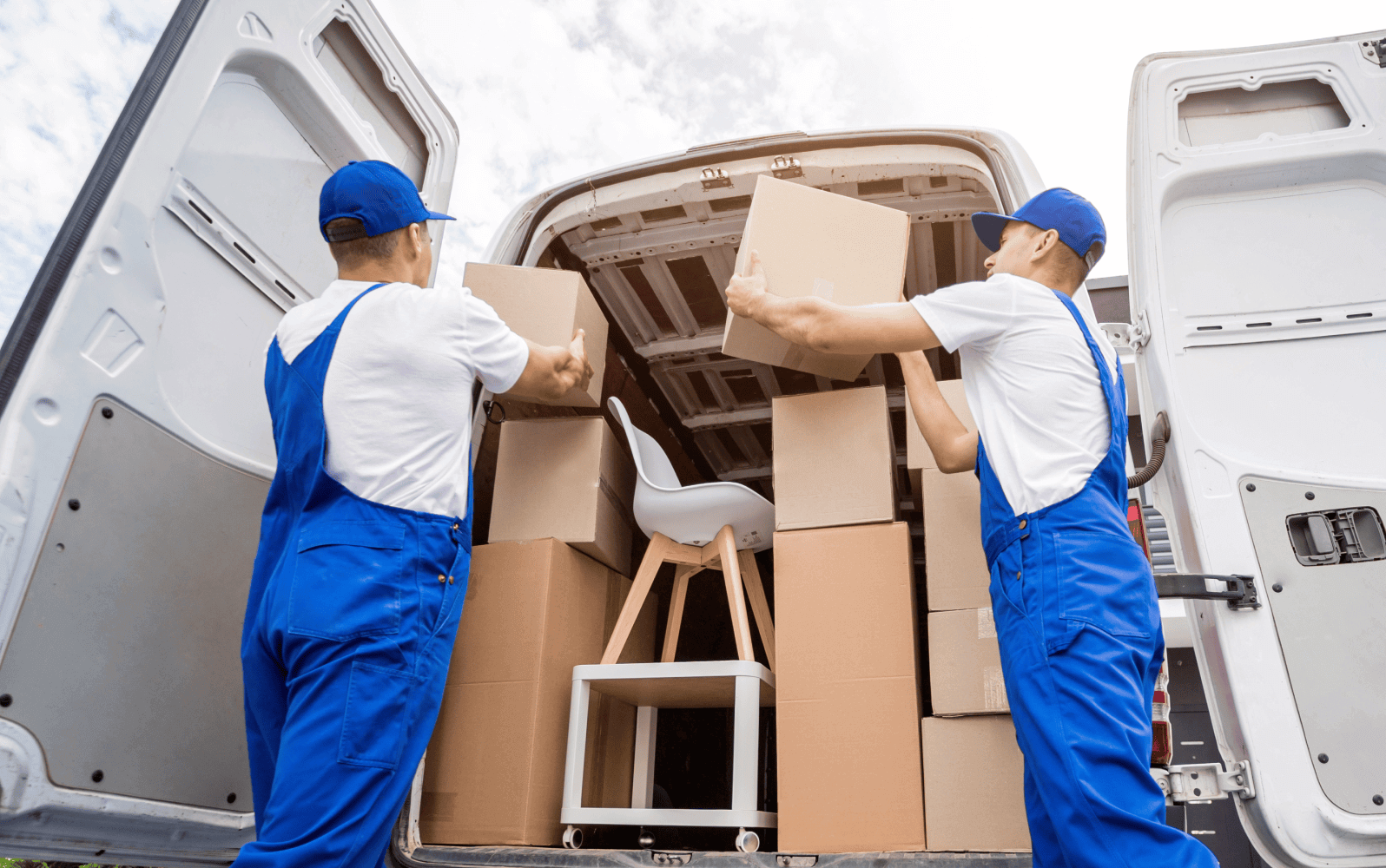 Two movers loading boxes into the back of a van