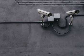Two security cameras mounted on a wall, providing surveillance. FIDO security card for Okta authentication visible.