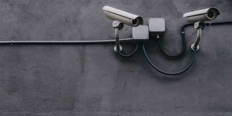 Two security cameras mounted on a wall, providing surveillance. FIDO security card for Okta authentication visible.