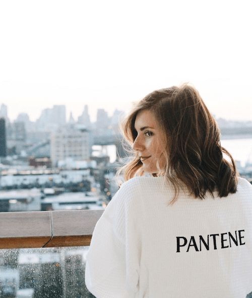 Maddy Haller leaning over a balcony in a white Pantene robe