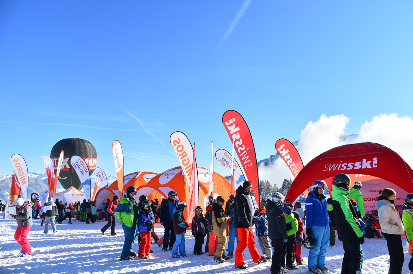 Famiglie che fanno la fila davanti agli stand di Swiss-Ski e della Migros in occasione del Migros Ski Day.