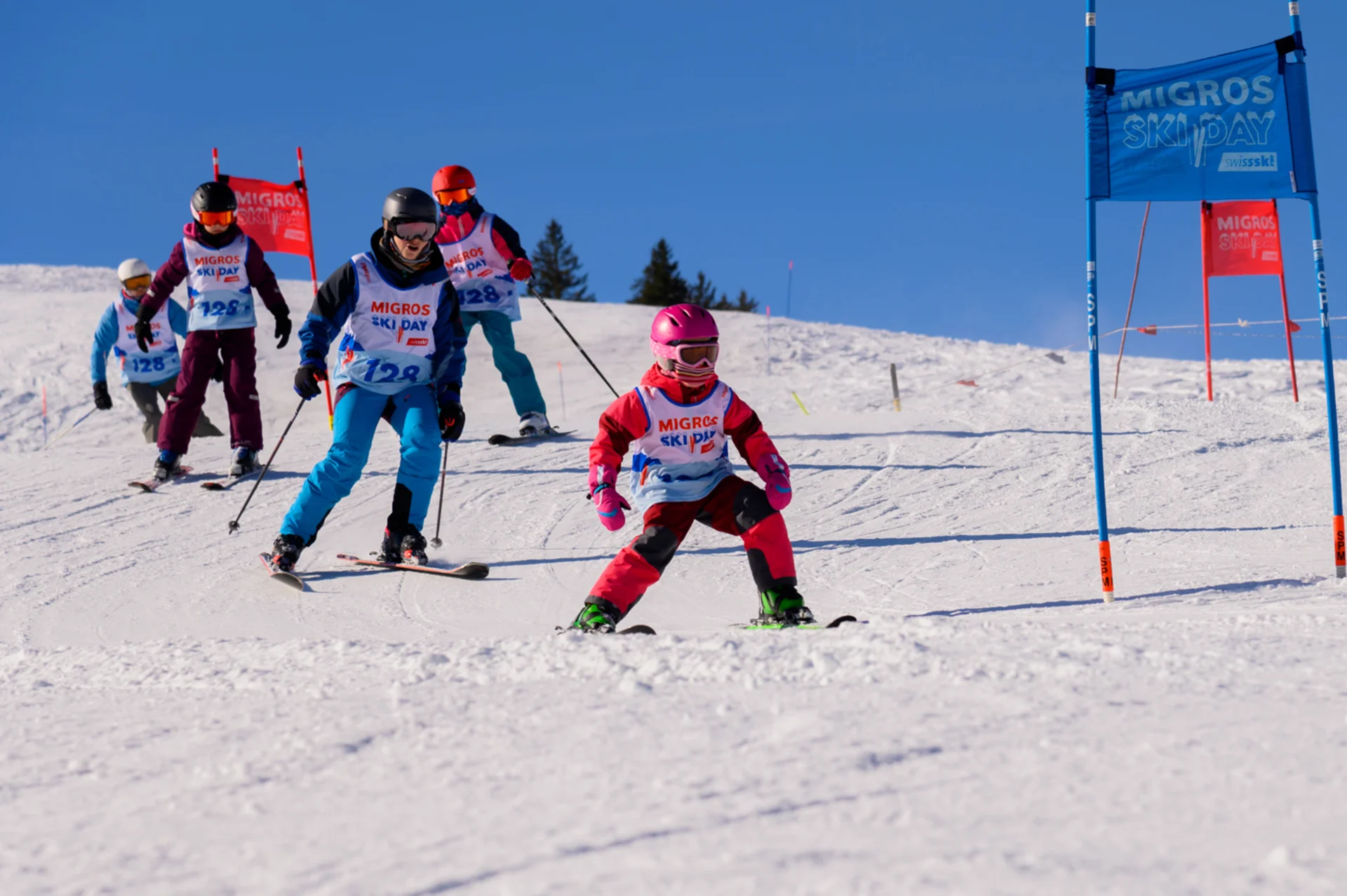 Familie fährt mit Ski einen Hang während des Migros Ski Days hinab.